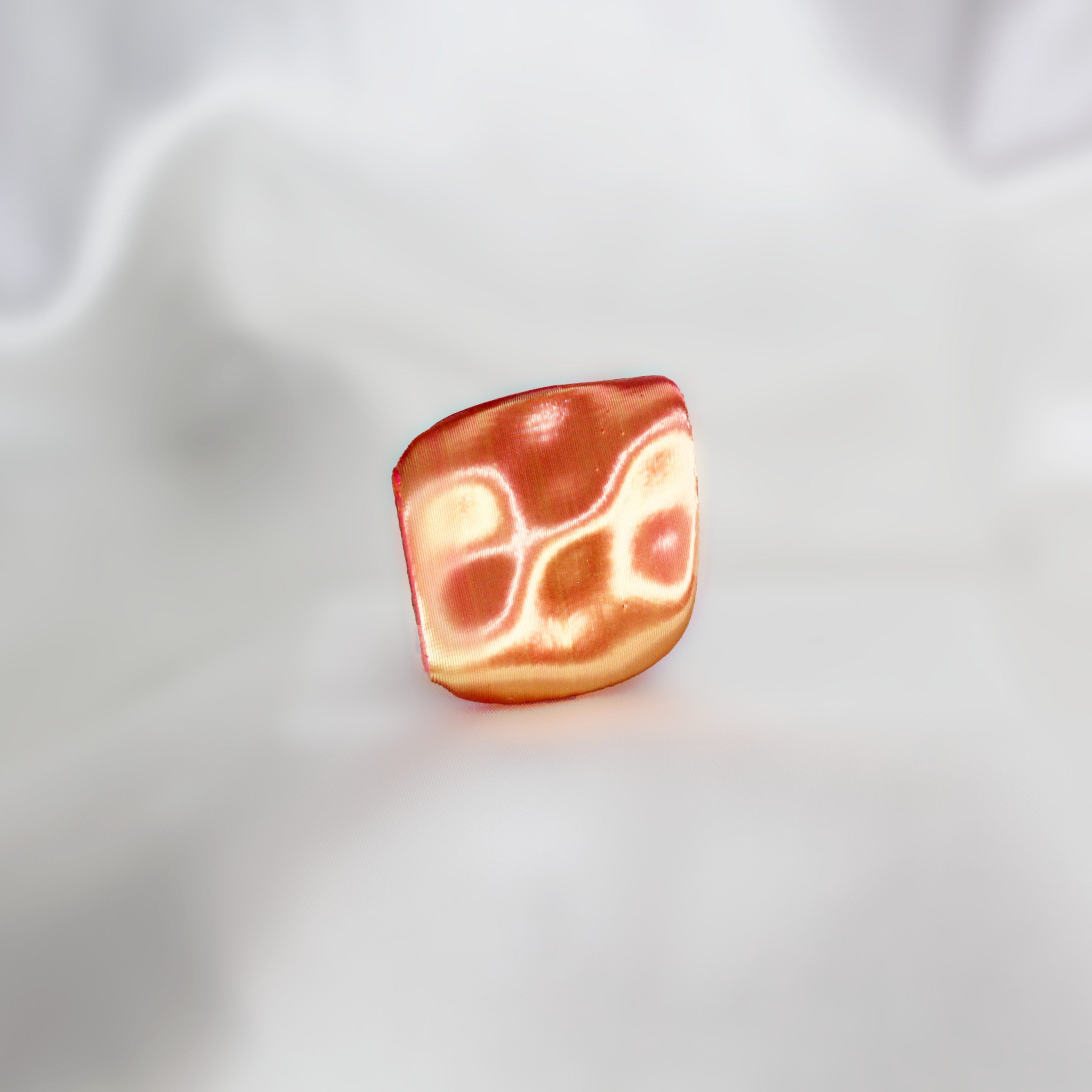 Bacon-shaped ring on a white fabric background