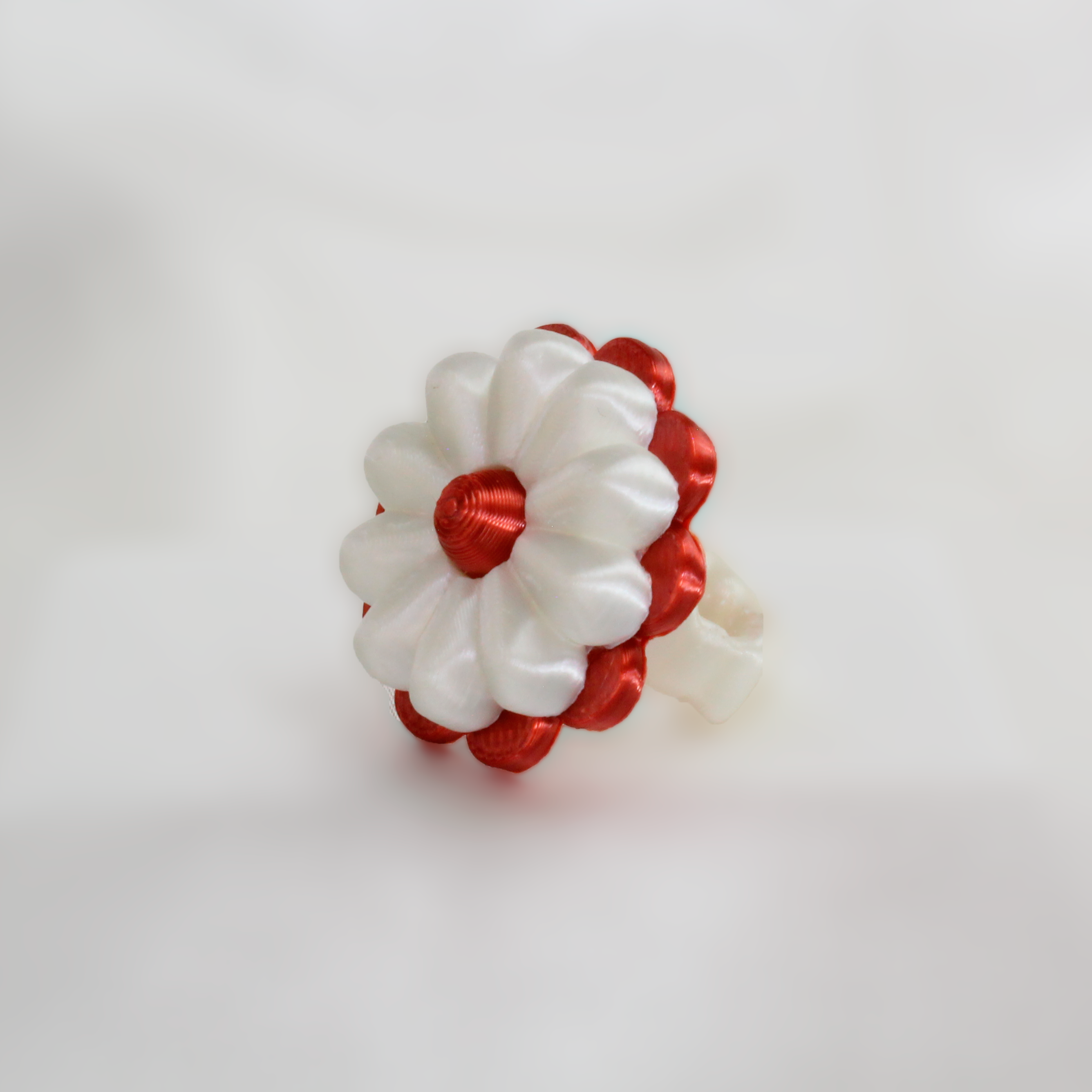 Red and white flower-shaped hair clip on a white fabric background