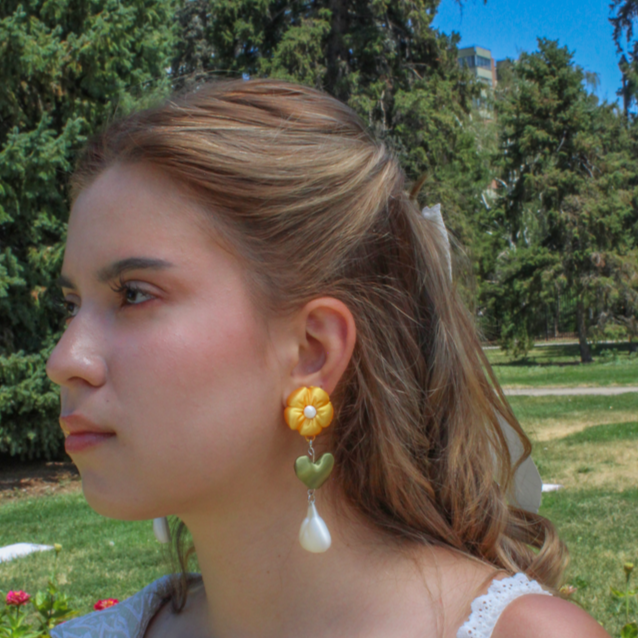 Woman wearing floral earrings and a ring in a park setting