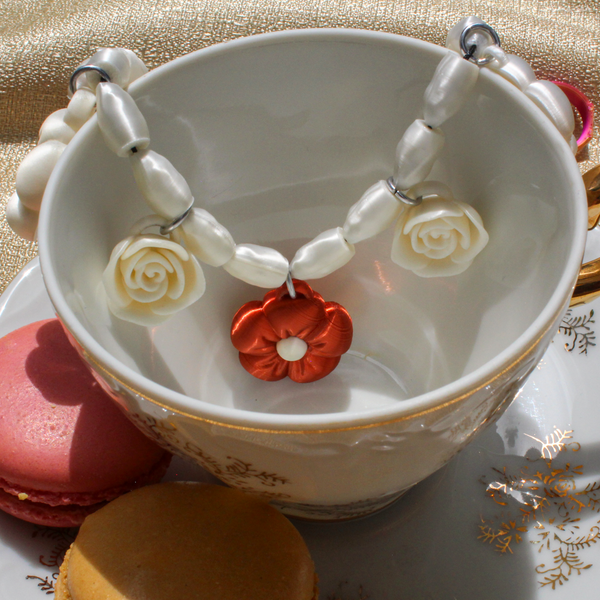 Teacup with decorative necklace and cookies on a gold fabric background